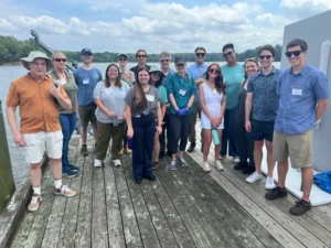 Members of the MACAN workshop smile at the camera while standing on a dock