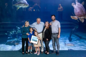 Ray smiles with his family in front of an aquarium tank
